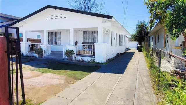 view of front of property featuring stucco siding, covered porch, and fence