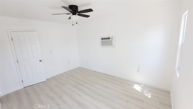 empty room with ceiling fan, a wall mounted air conditioner, and light hardwood / wood-style floors