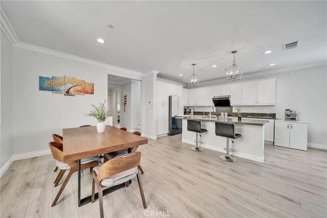 dining space with crown molding, light hardwood / wood-style flooring, a chandelier, and sink