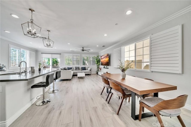 dining room featuring sink, light hardwood / wood-style flooring, a healthy amount of sunlight, and ornamental molding