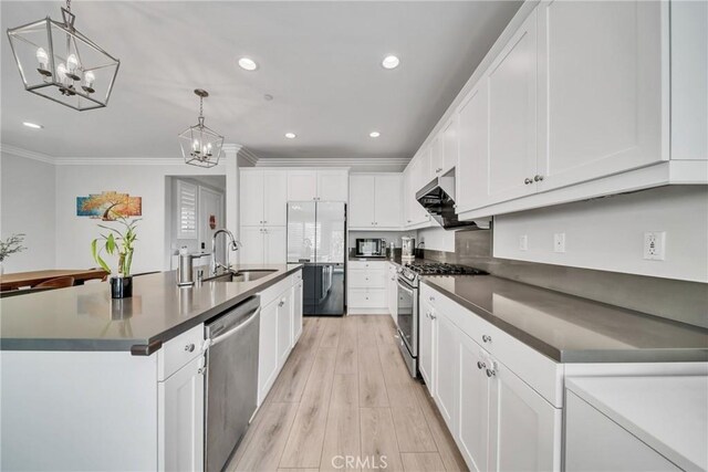 kitchen featuring white cabinetry, sink, hanging light fixtures, stainless steel appliances, and an island with sink