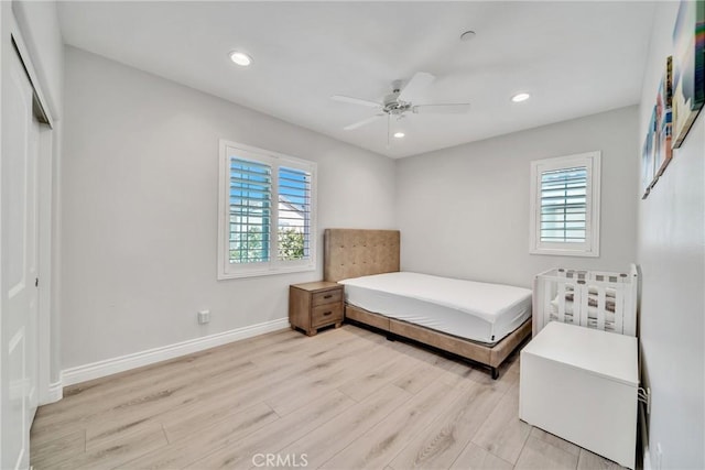 bedroom with multiple windows, light hardwood / wood-style floors, a closet, and ceiling fan