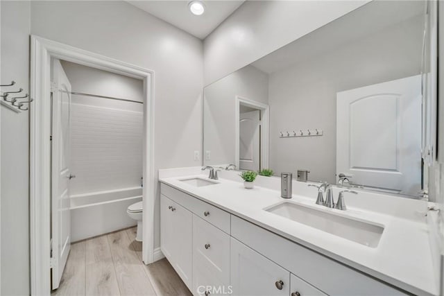 full bathroom featuring hardwood / wood-style floors, vanity, tub / shower combination, and toilet