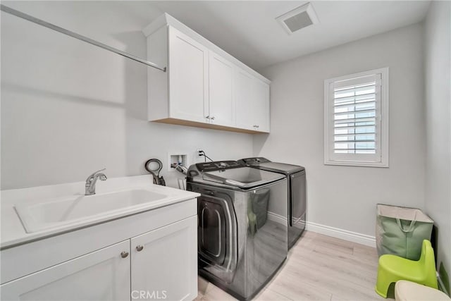 washroom featuring washer and dryer, light hardwood / wood-style floors, cabinets, and sink