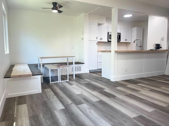 kitchen with kitchen peninsula, dark hardwood / wood-style flooring, ceiling fan, sink, and white cabinets