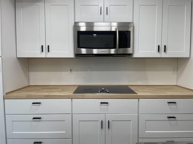 kitchen with white cabinetry, black electric stovetop, and wooden counters