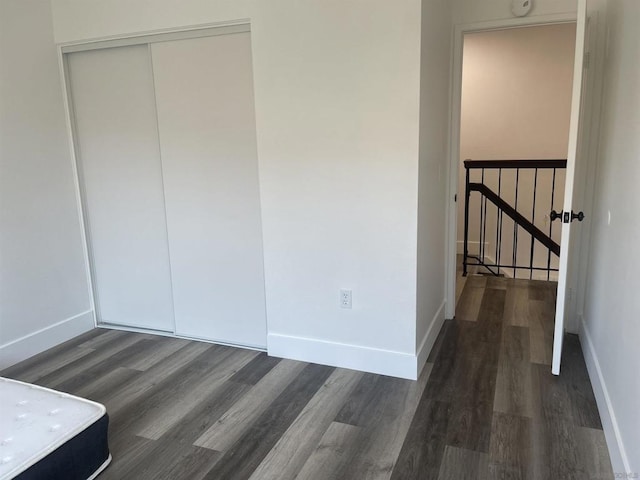 unfurnished bedroom with a closet and dark wood-type flooring