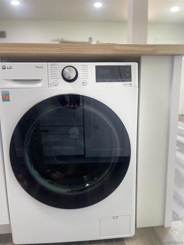 laundry room with washer / clothes dryer and light hardwood / wood-style flooring