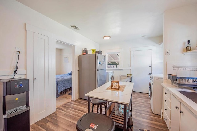 kitchen with stainless steel fridge, washing machine and dryer, and light wood-type flooring