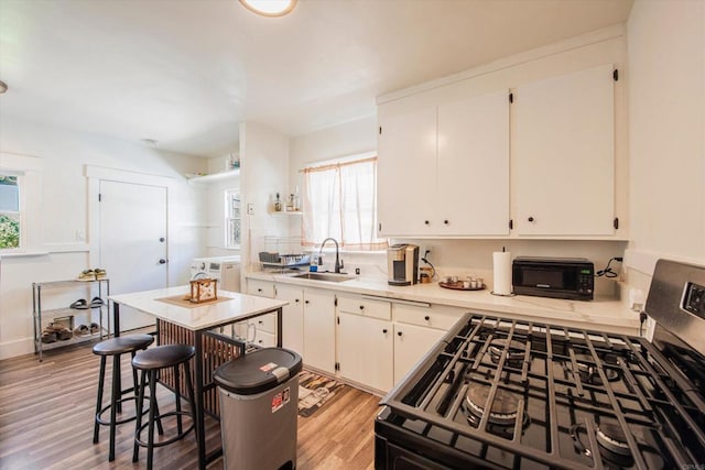 kitchen featuring light hardwood / wood-style flooring, stainless steel range oven, sink, and a wealth of natural light