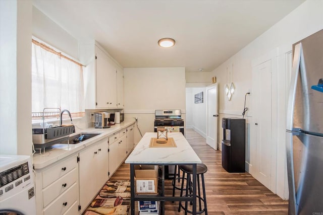 kitchen featuring washer / clothes dryer, white cabinets, stainless steel appliances, and dark hardwood / wood-style flooring