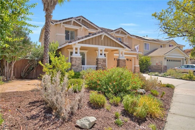 craftsman inspired home with stone siding, fence, covered porch, stucco siding, and a garage