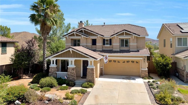 craftsman house with fence, stone siding, covered porch, an attached garage, and driveway