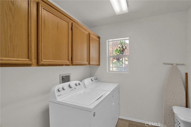 laundry area featuring separate washer and dryer, cabinet space, and baseboards