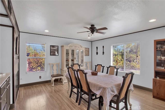dining area with a textured ceiling, ceiling fan, healthy amount of natural light, light wood-style floors, and baseboards