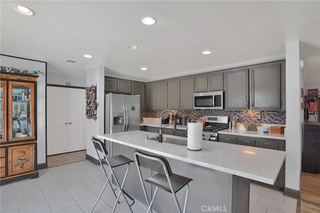 kitchen with stainless steel appliances, light countertops, decorative backsplash, and recessed lighting