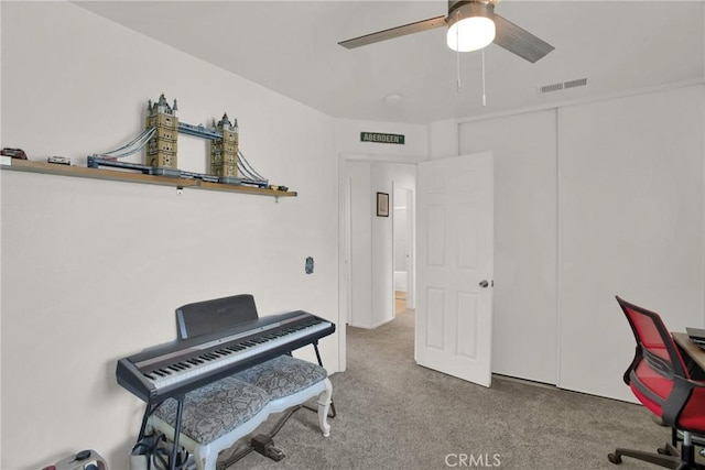 carpeted office space featuring ceiling fan