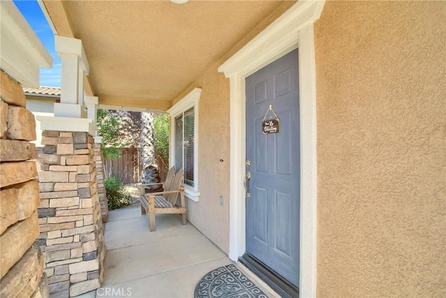 entrance to property with covered porch and stucco siding