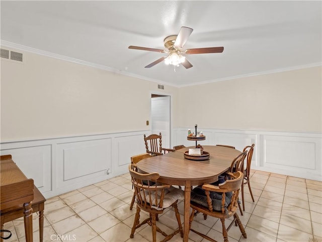 tiled dining area with ceiling fan and crown molding