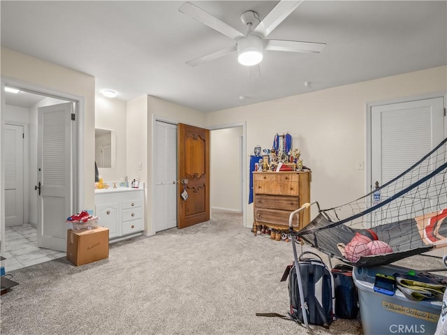 bedroom with ensuite bath, ceiling fan, and light colored carpet