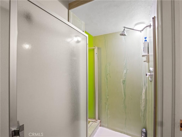 bathroom featuring a shower with door and a textured ceiling