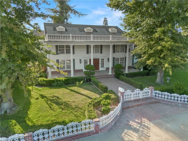 greek revival house featuring a front yard, french doors, and a balcony