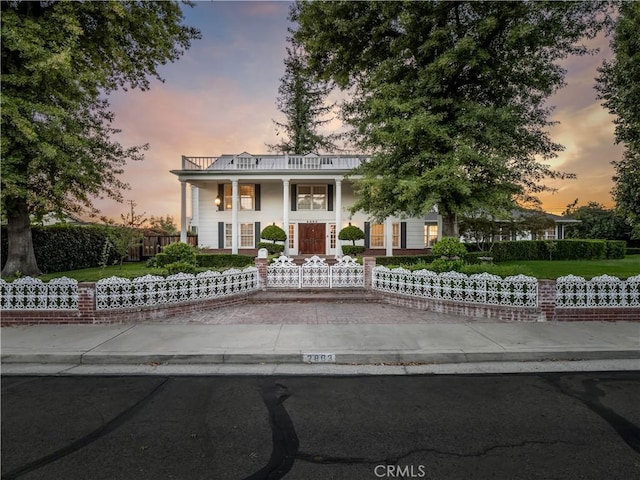 neoclassical home featuring a balcony and covered porch