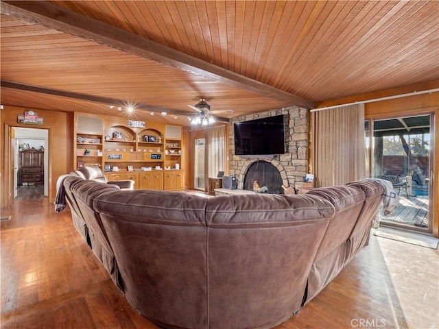 living room featuring ceiling fan, wooden ceiling, a stone fireplace, built in features, and light wood-type flooring