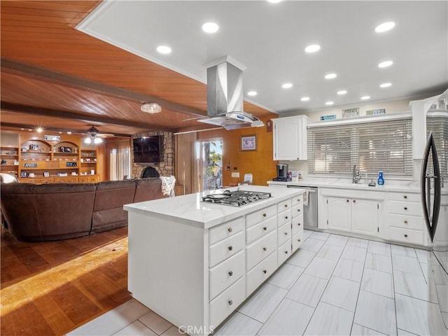 kitchen with appliances with stainless steel finishes, a center island, island range hood, and white cabinetry