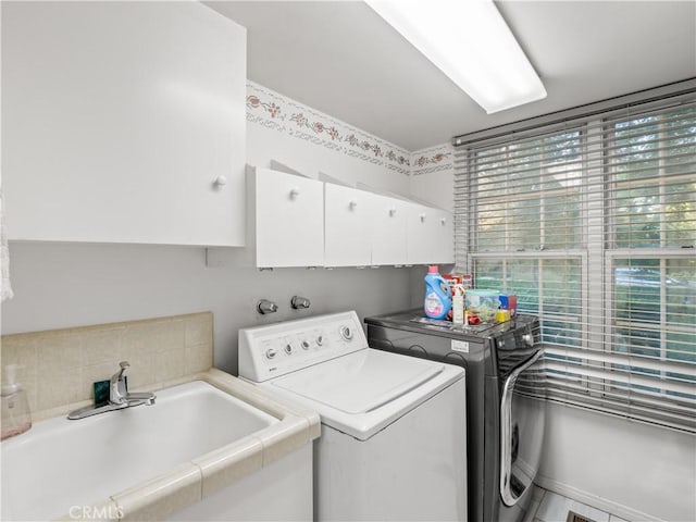 clothes washing area featuring sink, cabinets, and independent washer and dryer