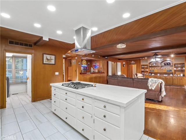 kitchen with wooden ceiling, a kitchen island, island range hood, white cabinetry, and stainless steel gas cooktop