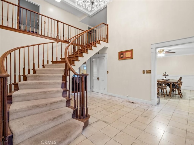 stairway featuring tile patterned floors, ceiling fan, and a high ceiling