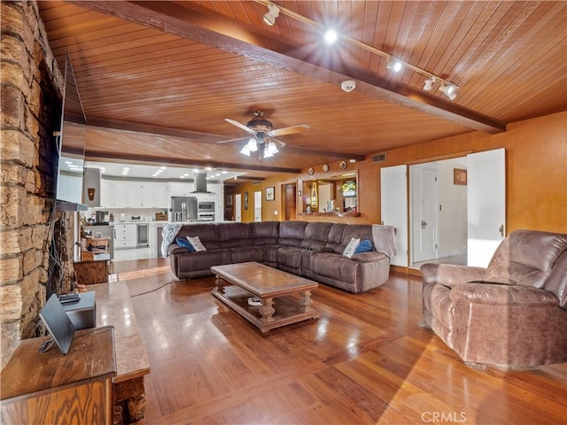 living room with beam ceiling, light wood-type flooring, rail lighting, and wooden ceiling