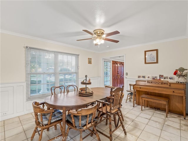 tiled dining space with ceiling fan and crown molding