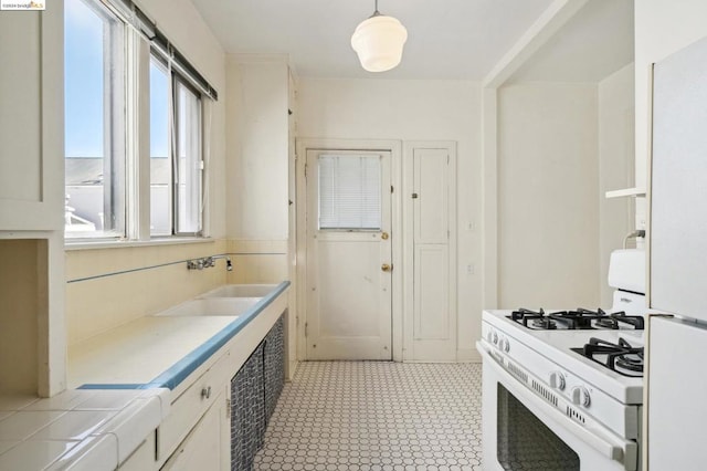 kitchen featuring tile counters, sink, white cabinets, white appliances, and decorative light fixtures