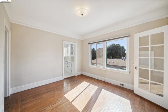 spare room featuring wood-type flooring and crown molding