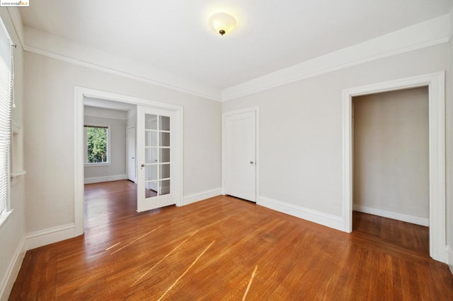 unfurnished room featuring french doors, hardwood / wood-style floors, and crown molding