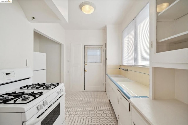 kitchen with sink, white appliances, and white cabinetry