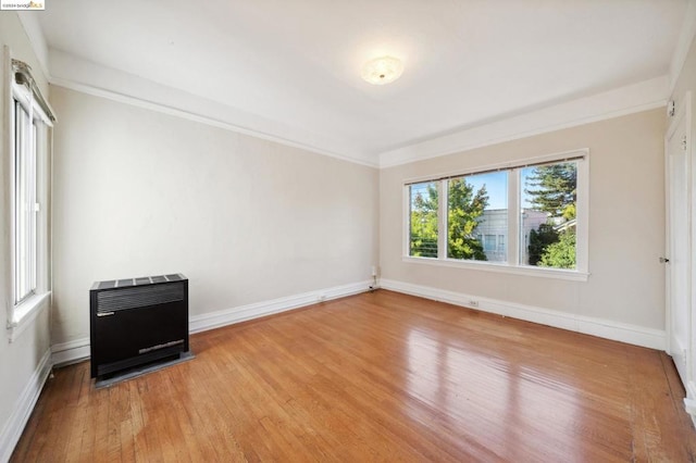 spare room with wood-type flooring, crown molding, and heating unit