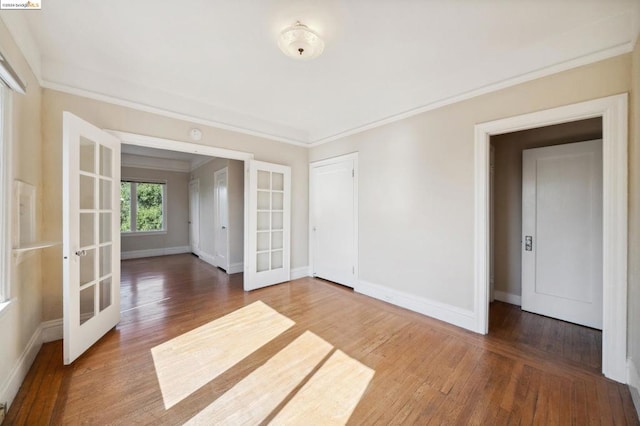 empty room with french doors, crown molding, and wood-type flooring