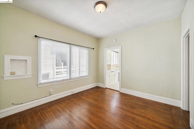 unfurnished bedroom featuring connected bathroom and dark hardwood / wood-style floors