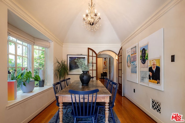 dining area with wood-type flooring, lofted ceiling, ornamental molding, and an inviting chandelier