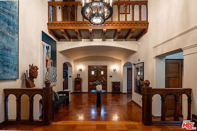 entryway with an inviting chandelier, high vaulted ceiling, and dark hardwood / wood-style flooring