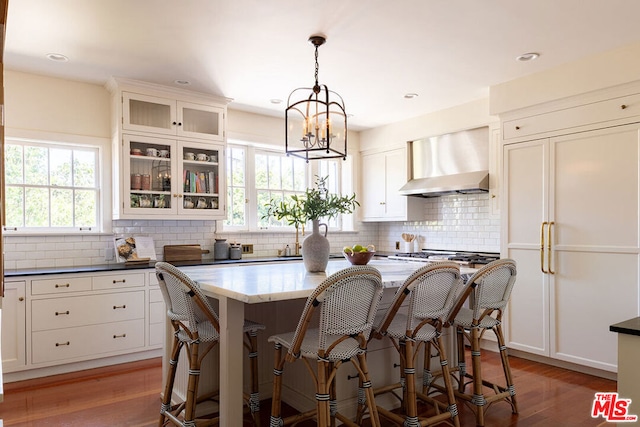 kitchen featuring wall chimney exhaust hood, dark wood-type flooring, and a healthy amount of sunlight