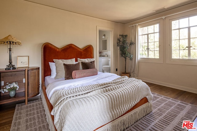 bedroom with dark hardwood / wood-style floors and ensuite bath