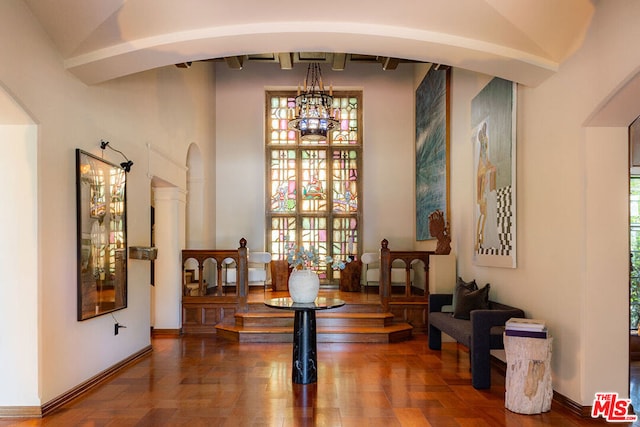 living area with an inviting chandelier, a towering ceiling, and ornate columns