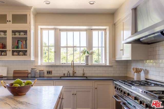 kitchen with white cabinets, sink, wall chimney range hood, and high end stainless steel range