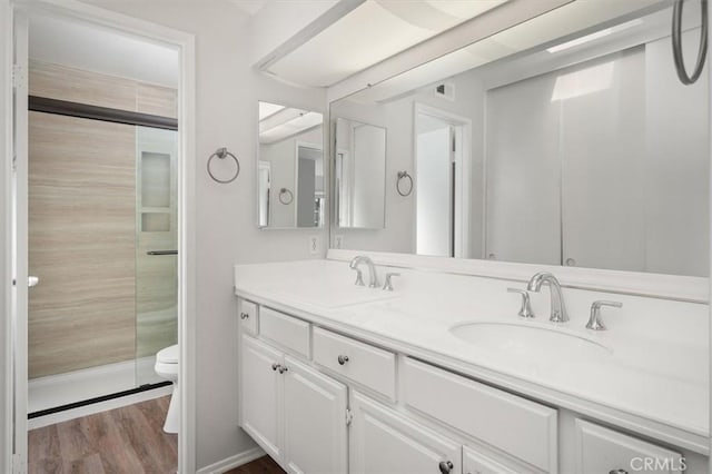 full bath featuring double vanity, wood finished floors, toilet, and a sink