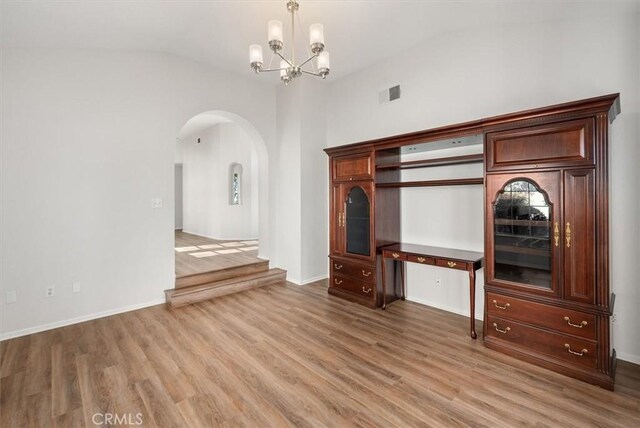 unfurnished living room featuring a notable chandelier, light hardwood / wood-style flooring, and vaulted ceiling