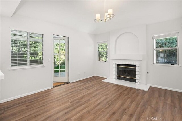 unfurnished living room with a fireplace, dark hardwood / wood-style flooring, and a notable chandelier